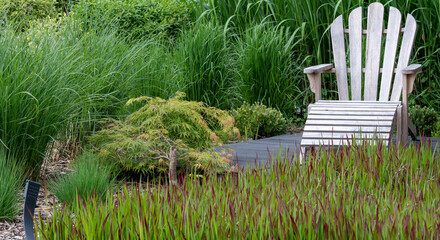 Fotel ogrodowy miejscem do wypoczynku , strefa relaksu w ogrodzie wśród traw i zieleni