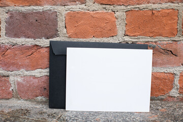 Mockup friendly template of postcard certificate with black envelope on a brick wall background