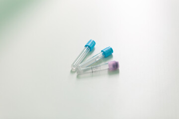 three empty medical plastic test tubes lie on a white medical table