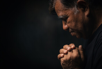 Elderly Asian man prayer to god on a black background. Old man praying to god for happiness and a...