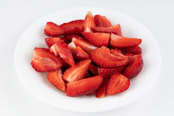 Ripe strawberries in slices on a white plate.Useful berries.