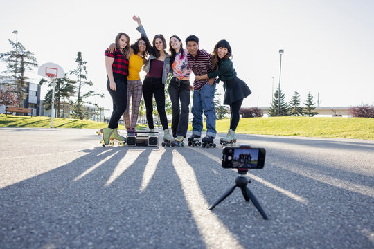 Multiethnic Friends Taking Photo On Rollerskates In Park