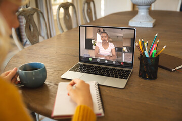 Multiracial female colleagues video calling while working though laptop in office