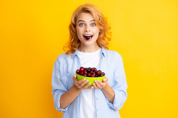 Portrait of woman with cherries on yellow studio isolated background.