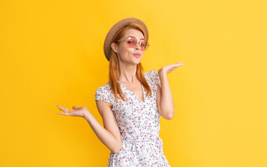 positive young woman in straw hat and sunglasses on yellow background