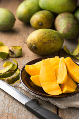 mango slices on a plate with whole mangoes in the background, taken in shallow depth of field