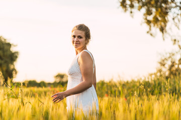 beautiful young woman with summery long dress walking in the field