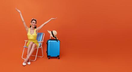 Beautiful woman relax sitting on a beach chair with suitcase in studio summer orange background...