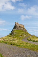 Lindisfarne/England: 10th Sept 2019: Holy Island Castle view from coastline with tide in blue sky