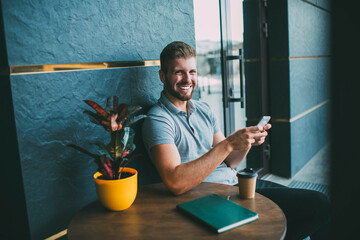 Happy stylish man with smartphone at table