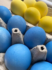 Easter eggs painted in the colors of the Ukrainian flag. Decoration for the festive table in traditional Ukrainian colors. Patriot colors. Colored eggs in a cardboard tray.