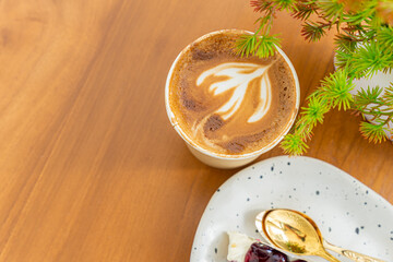 Hot coffee latte with latte art milk foam in cup made of paper and Blueberry Cake on wood desk on top view. As breakfast In a coffee shop at the cafe,during business work concept