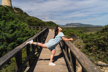 Fototapeta na wymiar Chica guapa joven posando alegremente junto a un faro en la costa de andalucia