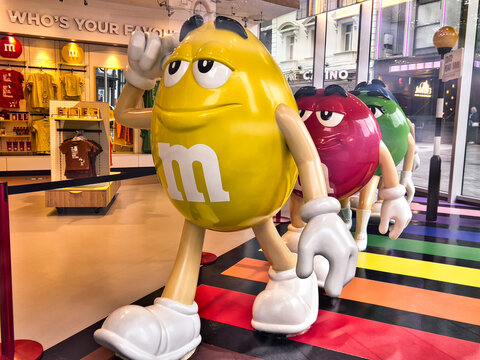 Large M&M Candies Walk Across A Rainbow Cross Walk Inside An M&M Shop In London, England 