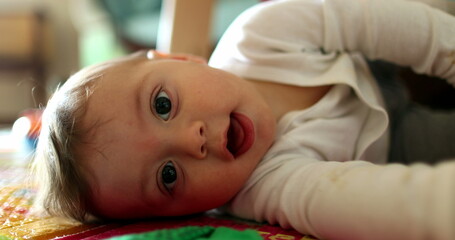 Cute baby lying on floor looking to camera, toddler child portrait