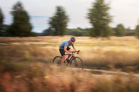 Cyclist in motion. Young sporty man rides gravel bike along the trail in the field. Blurred motion. Sport and travel.