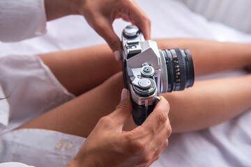 young woman placing roll of film on analog camera