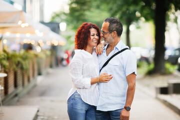 Cute European middle-aged couple hold hands and walk through the streets of the city,, summer walks...