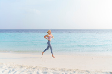 A sporty woman runs along the beach.