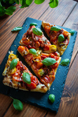 Tomato puff pastry tart with balsamic vinegar and fresh basil on stone plate