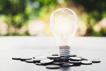 Light bulb and stack of coins on the desk. Saving energy and money