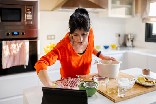 Woman Cooking cake and using the tablet at kitchen