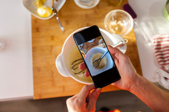 Woman taking photo of food with mobile phone in kitchen
