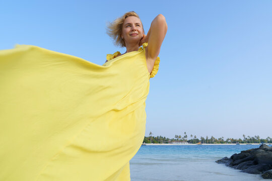 Portrait of a woman in a yellow dress on the ocean.