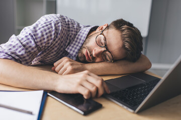 Millennial businessman sleeping at desk in office