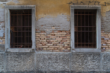 Fototapeta na wymiar old wall with exposed bricks and two large windows in Italy 