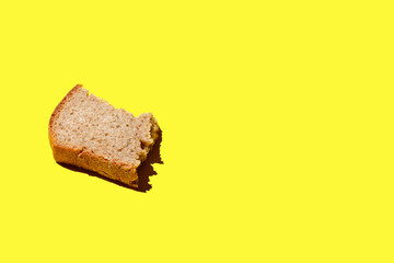 piece of black bread on a yellow background,  crust of bread, black bread with sliced slice