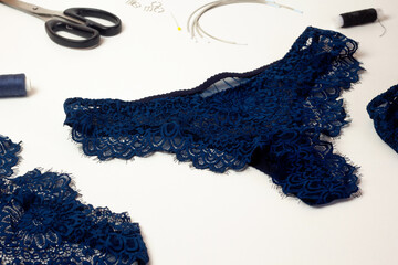 Blue lace lingerie, female panties, tailor workplace equipment fabric, scissors, thread. Handmade underwear workshop
