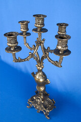 classic bronze chandelier on a blue background, ancient candlestick studio photo, antique candlestick isolated, brass chandelier, one vintage candlestick, bronze candle tree on blue background