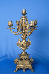 classic bronze chandelier on a blue background, ancient candlestick studio photo, antique candlestick isolated, brass chandelier, one vintage candlestick, bronze candle tree on blue background