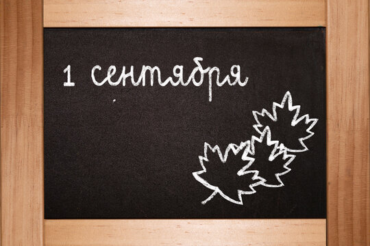 The concept of the beginning of the school year. On a black black blackboard, chalk is written in Russian language on September 1 - Powered by Adobe