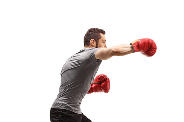 Profile shot of a young man punching with boxing gloves