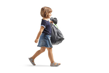 Full length profile shot of a little girl walking and carrying a waste bag