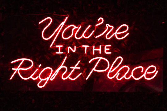 Photograph of a red neon sign on which the word "" can be read " You´re IN THE Right Place" - Powered by Adobe