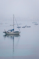 sail boat anchored in the harbour on a foggy morning