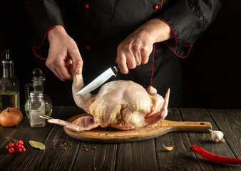 The chef cuts raw chicken with a knife. National cuisine. Menu idea for a hotel or restaurant