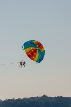 Couple paragliding in a coloured parachute