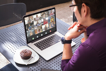 Aziatische jonge zakenman die laptop in café gebruikt tijdens online ontmoeting met multiraciale collega& 39 s