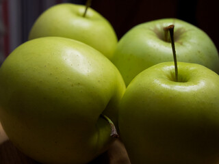 Four large apples, close-up. Fruit on a wooden surface.
