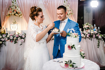 Bride and a groom is cutting and eating their rustic wedding cake on wedding banquet. Hands cut the...
