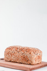 Fresh warm bread with sesame seeds on a wooden board. Healthy baked bread on a white background. Copy space.