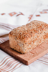 Freshly baked bread with sesame seeds on a wooden board. Healthy baked bread on a tablecloth.