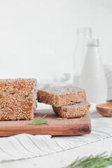Breakfast with freshly baked sesame bread and milk. Whole grain bread on a wooden board. Gluten free bread. Copy space.