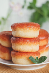 Stacked fresh donuts with mint on a plate on a yellow tablecloth. Sweet fast dessert concept.