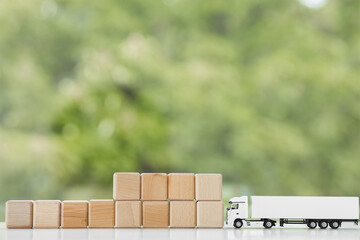 Flat lay composition of toy truck with wooden cubes on green background. Logistics and wholesale concept