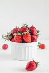 White ceramic bowl with fresh red strawberries on a white table. Natural organic berries.